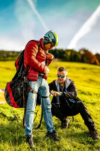 Flight instructor helps a paragliding student prepare for take-off on the practice slope to ensure a safe and successful take-off.