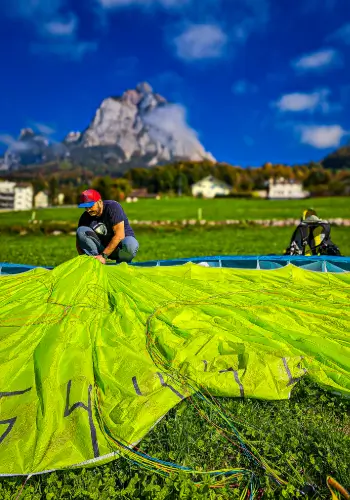 Pilot im Baseballcap packt seinen Gleitschirm zellengenau nach der Landung vor den Mythen – Symbol für den Abschluss eines erfolgreichen Paragliding-Flugs bei touch and go Paragliding.