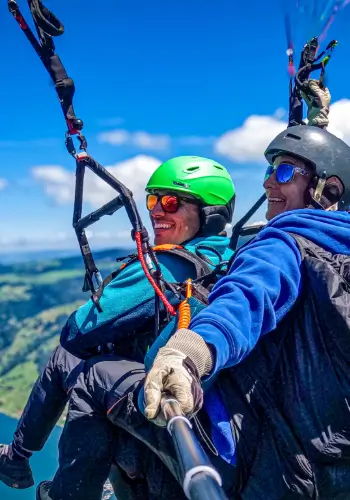 Passenger and tandem pilot laugh together during a tandem flight with touch and go paragliding.