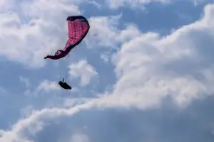 Pilot simulates a side collapse during touch and go paragliding safety training under the guidance of experienced instructors.