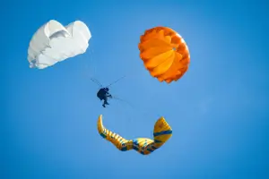 Pilot throws his emergency parachute over the water during touch and go paragliding safety training.