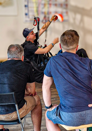 The flight instructor demonstrates the maneuvers during the maneuver briefing in the simulator during the training at touch and go paragliding.