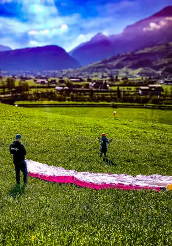 The participant of the team building day is ready to take off for his first short flight with his paraglider on the practice slope, accompanied by an experienced flight instructor from the touch and go paragliding school.