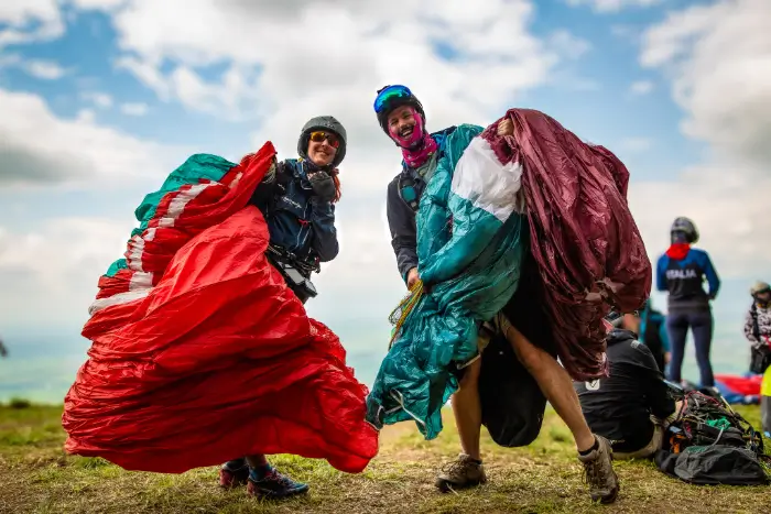 Eva Maranta, travel guide from touch and go Paragliding, stands with a participant at the launch site in Colombia and prepares for a cross-country flight.