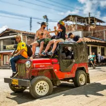Off-roader with paraglider pilots on the roof, hood and loading deck on the way to the launch site in Colombia - pure adventure.