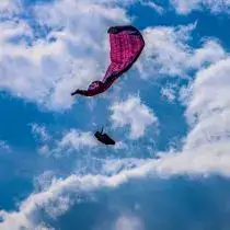 Pilot practicing a side collapse during touch and go paragliding safety training under the guidance of experienced instructors.