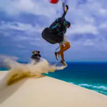 Pilot playing with his paraglider in the sand on the dune.
