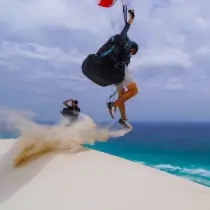 Pilot playing in the sand on the dune with his Nova paraglider.