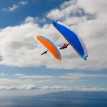 Two Nova paragliders in flight over central Switzerland. Experience the freedom of paragliding with touch and go paragliding.