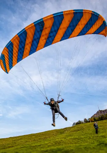 A student takes off with a phi paraglider and starts his first small flight on the practice slope under the guidance of an experienced flight instructor.