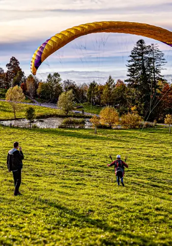 A paragliding student takes off for his first short flight on the practice slope, accompanied by an experienced instructor from touch and go Paragliding.