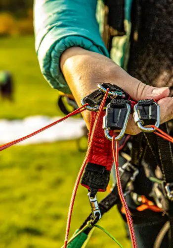 A pilot holds the risers of his paraglider in his hand - a symbol of safe preparation and full control before take-off.
