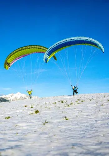 Two paraglider pilots prepare for take-off on the practice slope - full of adventure and under professional guidance.