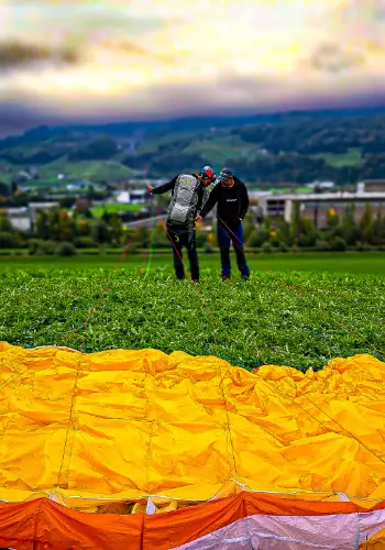 Flight instructor helps a paragliding student prepare for take-off on the practice slope to ensure a safe and successful take-off.