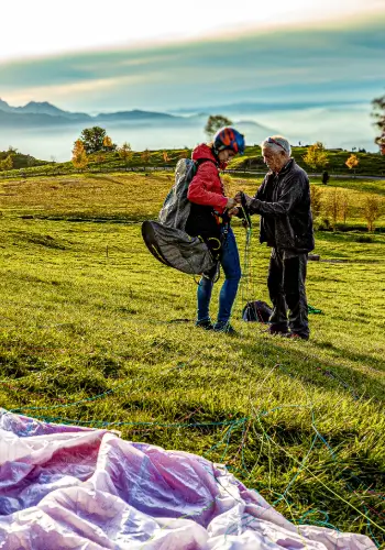 Flight instructor helps a paragliding student prepare for take-off on the practice slope to ensure a safe and successful take-off.