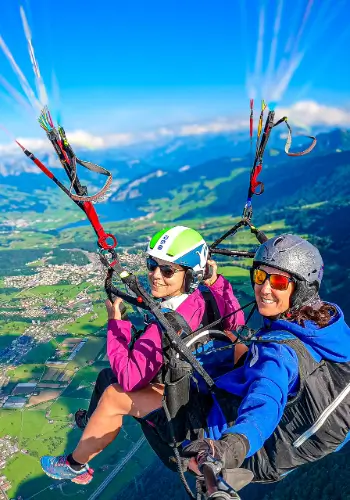 Tandem pilot with student pilot paragliding over the impressive mountain landscape and lakes of Central Switzerland, surrounded by clear air and breathtaking views.