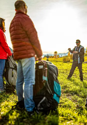 A touch and go instructor holds a briefing on the practice slope to introduce the students to the basics of paragliding.