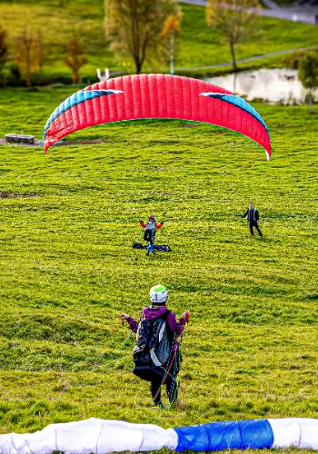 A paragliding student takes off for his first short flight with his Niviuk paraglider on the practice slope, accompanied by an experienced flight instructor from the touch and go paragliding school.