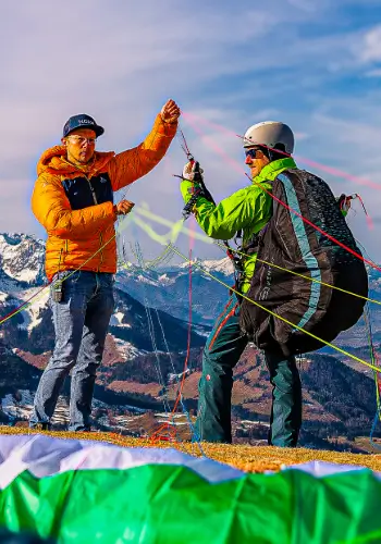 Paragliding students at the launch site while the instructor carefully checks the equipment and lines to ensure a safe launch.