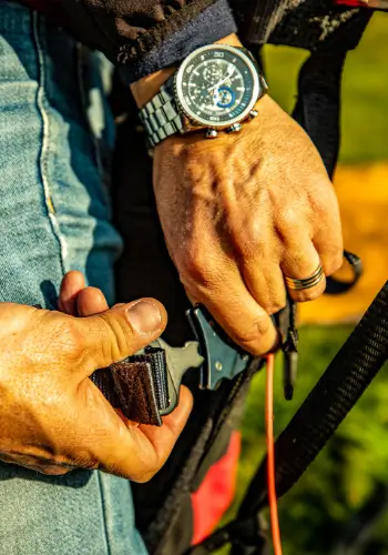 Pilot schließt das Gurtzeug vor dem Start während der Gleitschirmausbildung bei touch and go Paragliding.