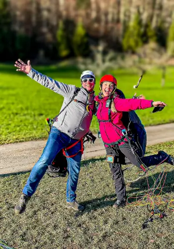 Zwei glückliche Schüler am Landeplatz nach der erfolgreichen Landung während der Ausbildung bei touch and go Paragliding in Wolfenschiessen.