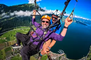 The student takes the controls of a tandem paraglider while the instructor gives instructions.