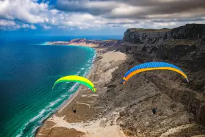 Paraglider pilots soar along the coast over the sea and take advantage of the dynamic upwind current.