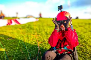 Pilot at the launch site laughs and jokes around before taking off into the sky with her paraglider, surrounded by a relaxed atmosphere.