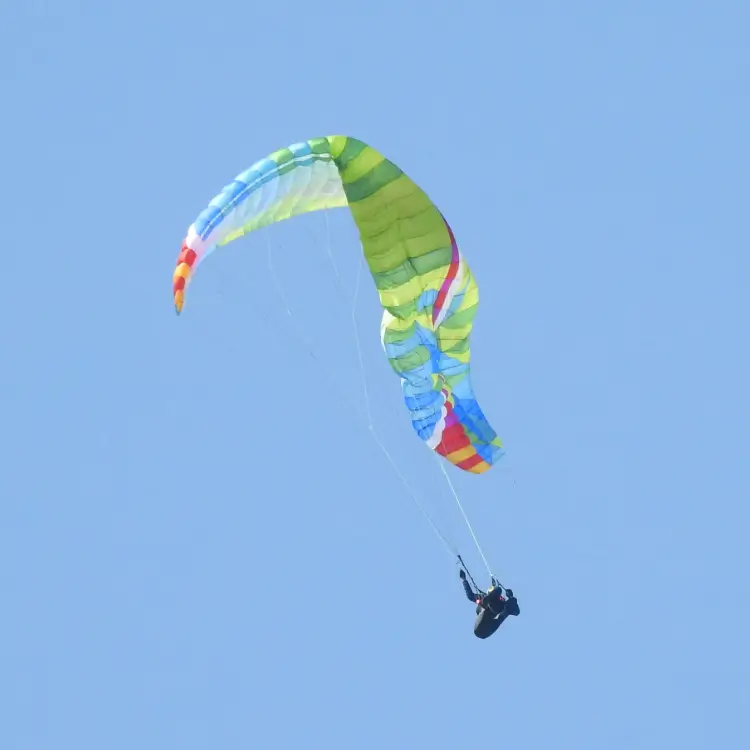 Paraglider with a visible rattle in the air - symbolizing the importance of safety training, G-force training, ground handling and cross-country seminars.