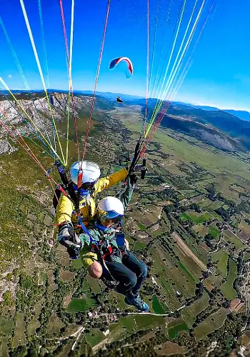 Paraglider pilot soars over the picturesque hills of Bosnia during the Bosnia tour of touch and go paragliding.