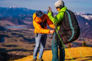 Paragliding students at the launch site while the instructor carefully checks the equipment and lines to ensure a safe launch.