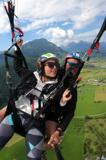 Passagierin übernimmt das Steuer während eines Tandemflugs mit touch and go Paragliding.