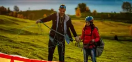 Flight instructor checks the lines of a paraglider on the practice slope during training at touch and go paragliding.
