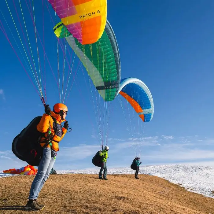Drei bunte Gleitschirme am Startplatz, kurz bevor sie abheben um über der atemberaubenden Berglandschaft der Zentralschweiz bei idealen Wetterbedingungen zu fliegen.