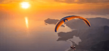 Gleitschirmflug während des Sonnenuntergangs über Ölüdeniz mit touch and go Paragliding.