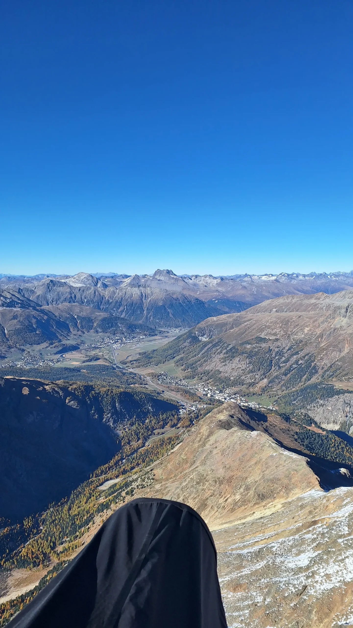 Paraglider pilot flies over the Upper Engadine valleys with a wide panoramic view of the mountains.