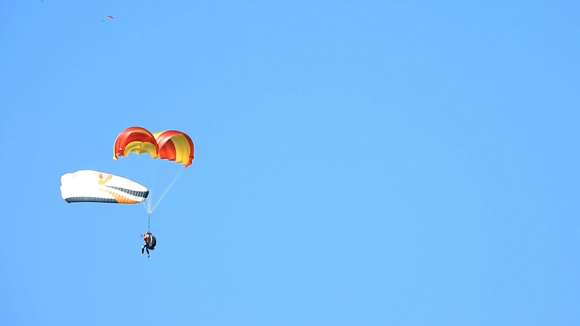 Pilot under paraglider with opened emergency parachute Beamer 3 Light in the air.