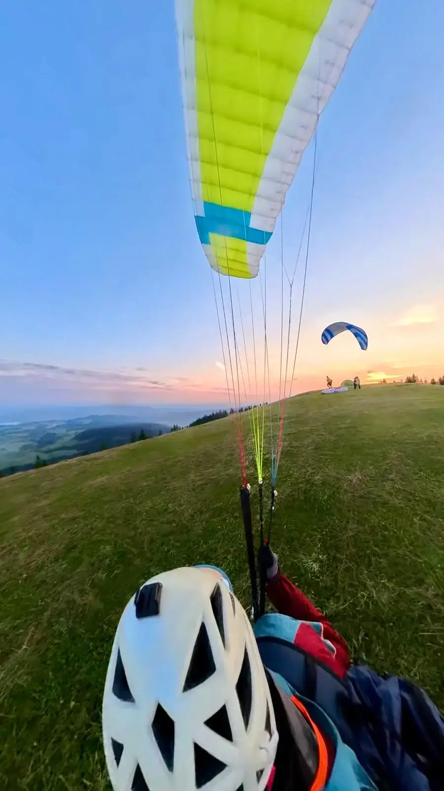Zwei Paragleiter am Startplatz Gnipen beim Kiten ihrer Schirme vor dem Start – lebendiger Wind und Vorbereitung auf den Flug.