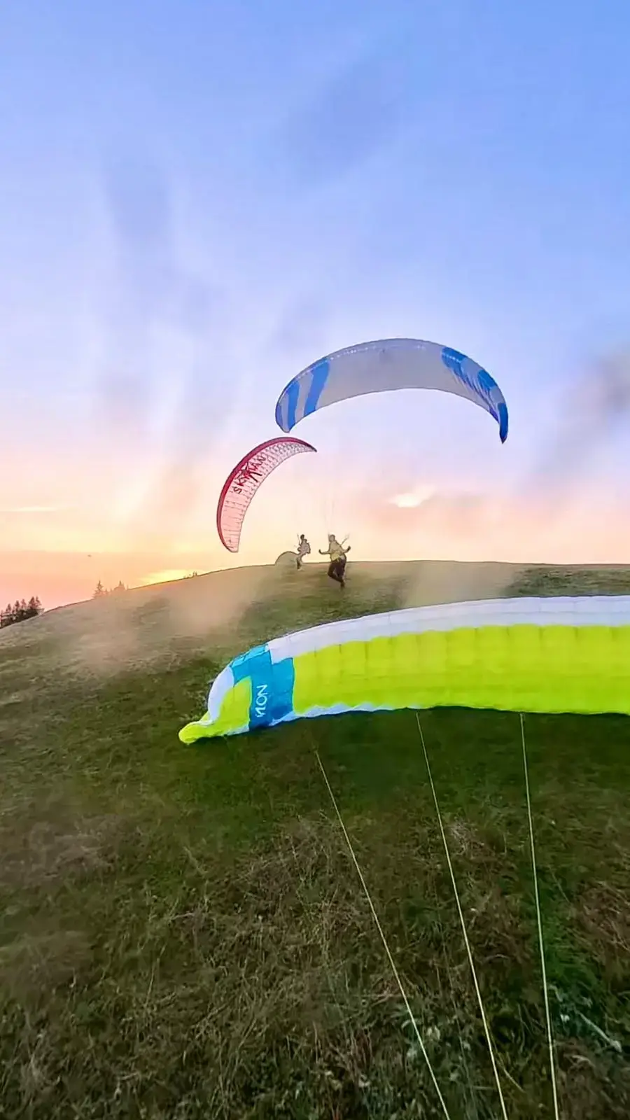 Zwei Leichtschirme am Startplatz Gnipen nach dem Hike & Fly – Wind, Startvorbereitungen und bereits fliegende Piloten über dem Vierwaldstättersee.