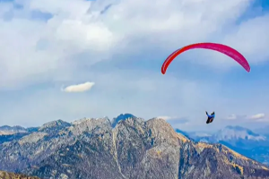 Gleitschirmflieger über den Alpen bei Bassano del Grappa, Italien, mit Panoramablick auf Berge und Täler