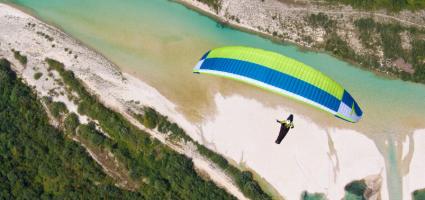 Gleitschirmflieger über dem smaragdgrünen Fluss Soca in Slowenien, mit Blick auf Berge und Natur